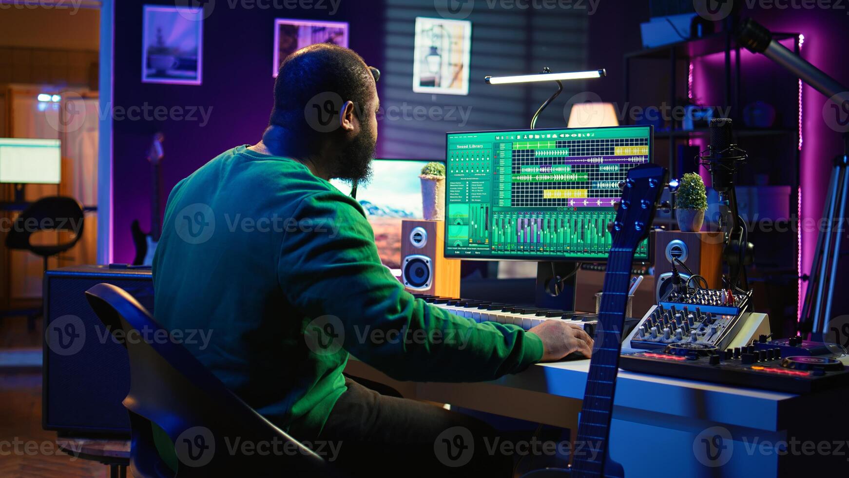 Musical producer prepares to record tunes on acoustic instrument, working in personal home studio to record soundtrack. Sound composer recording guitar music, editing with mixing console. Camera B. photo