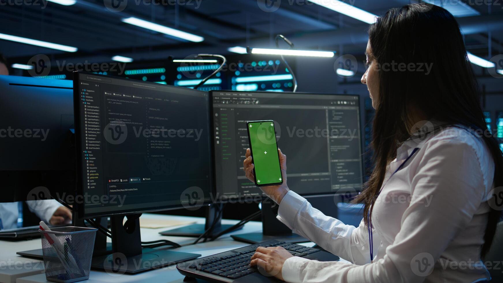 Worker overseeing data center using green screen mobile phone, ensuring system can handle networking tasks. IT expert in server room tracking network traffic with empty copy space smartphone, camera B photo
