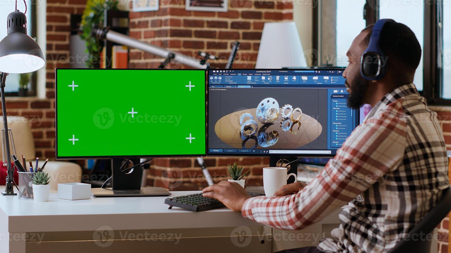 Software developer creates a gear prototype on dual monitors next to chroma key display, home office remote work. Expert does 3D modeling for innovation in the industrial design industry. Camera B. photo