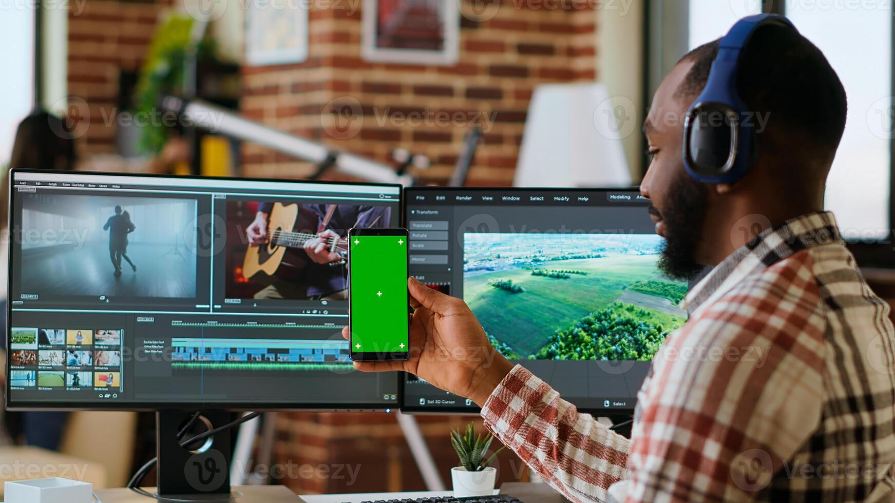 Male editor works on a movie project in a creative software next to chroma key, multitasking between timeline editing and color grading using dual monitors and tech tools. Camera B. photo