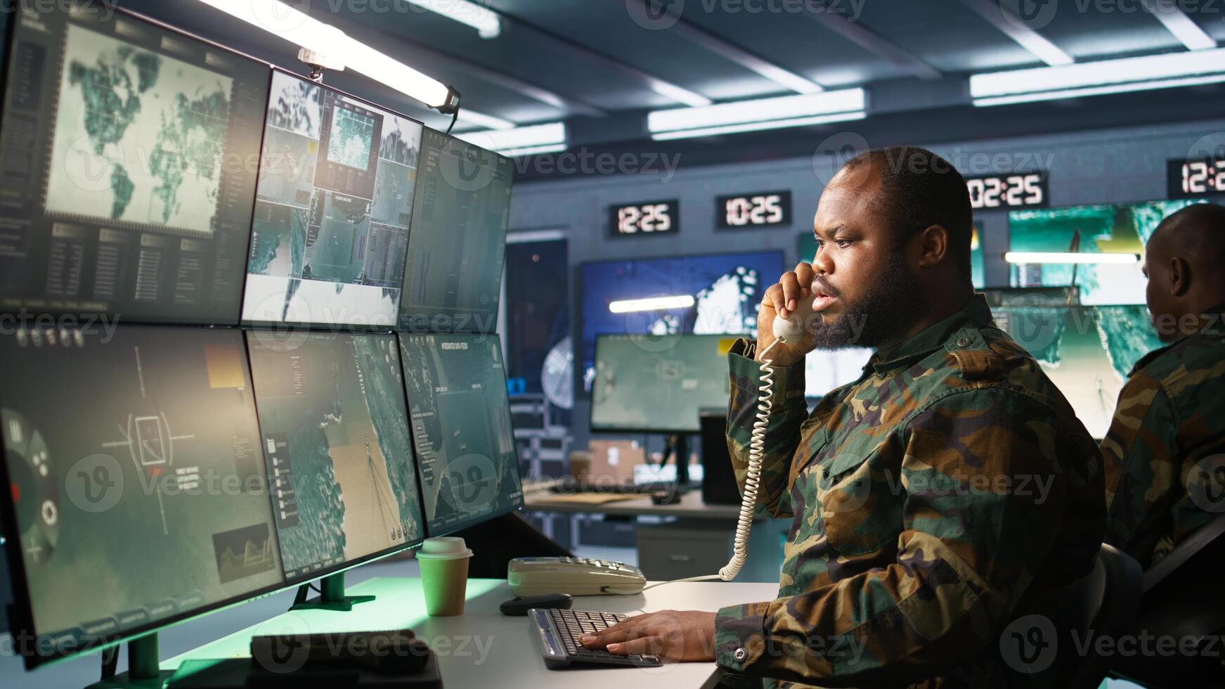 Military soldier in mission command post overseeing national safety operations, talking on phone. African american army expert in telephone call in monitoring room, camera B photo