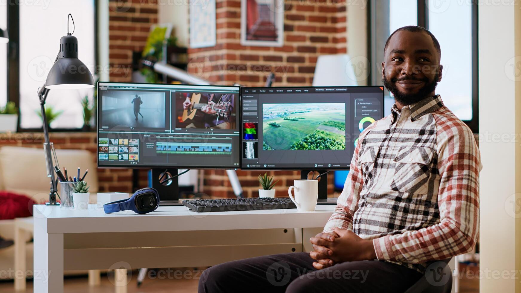 African american male filmmaker works with creative editing software, mixing and color grading clips. Living room workspace features post production tools and dual monitors. Camera B. photo