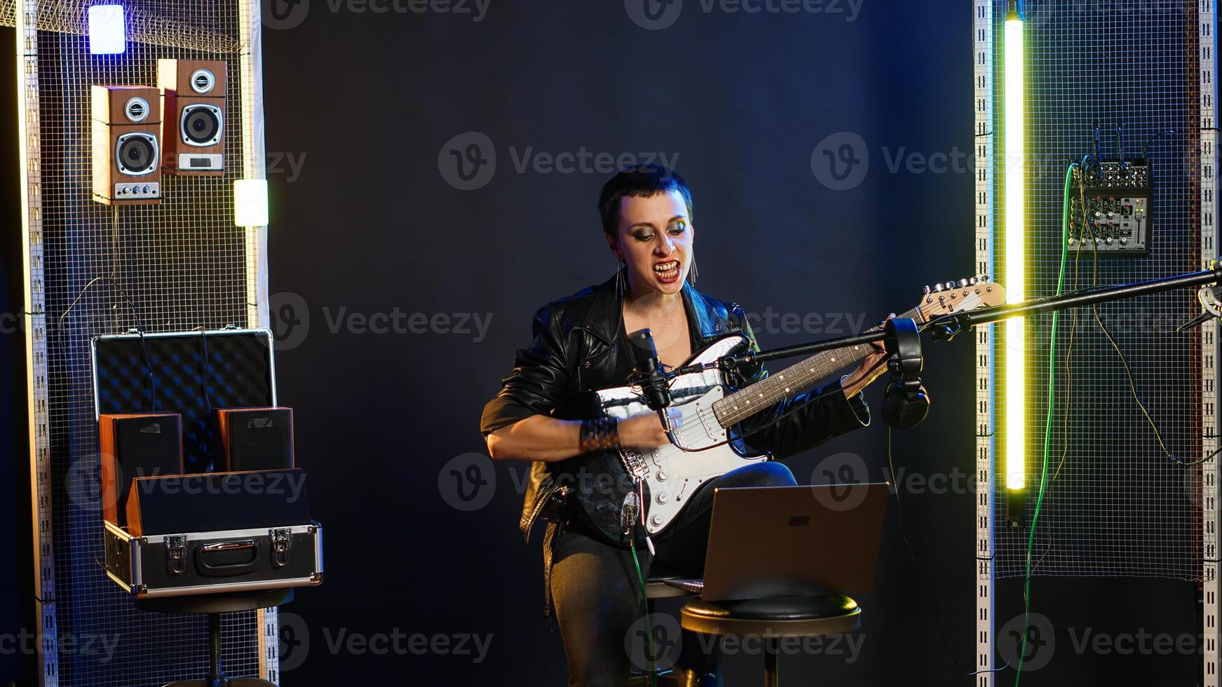 Annoyed female performer getting her vocals wrong during pre show rehearsal, doing musical warm up at practice session in the studio. Grunge rock star does performance prep. Camera B. photo
