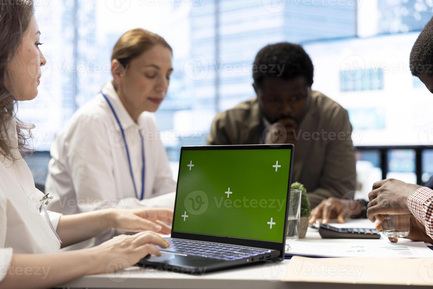 Diverse enterprise staff using a laptop with copy space display during a briefing meeting, establishing the future of the multinational company. Employees and managers in a conference. photo