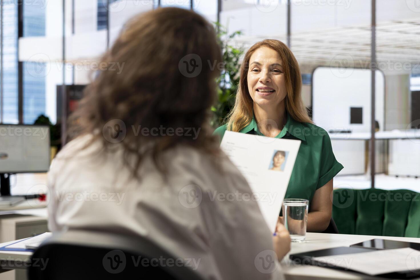 Human resources manager holding applicant CV, sitting at workplace desk during corporate office meeting. HR employer searching and selecting candidates to work for organization photo