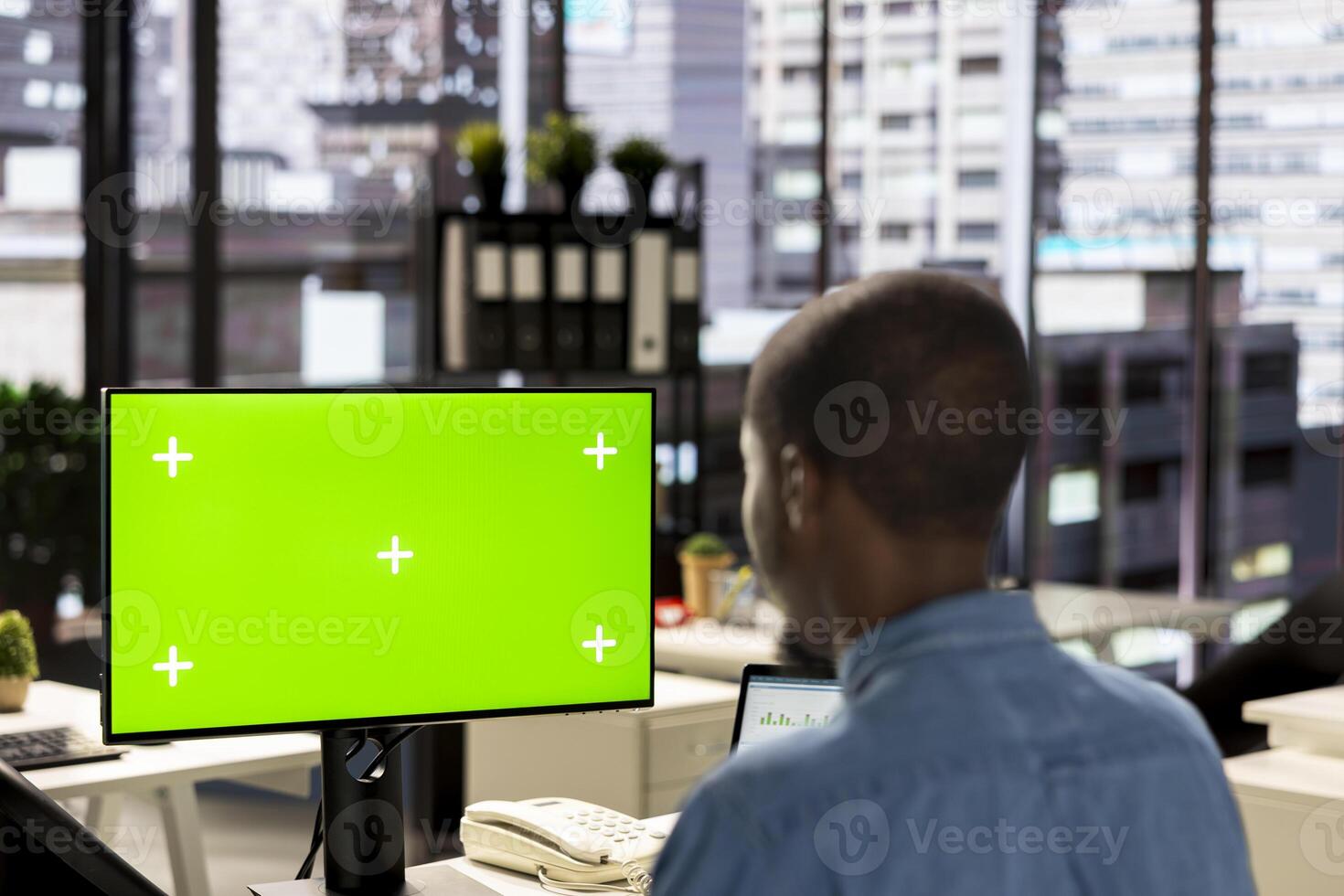 Male business manager at desk looking at mockup screen and solving tasks for company objectives accomplishment. Fighting for performance goals to ensure successful corporate outcomes. photo