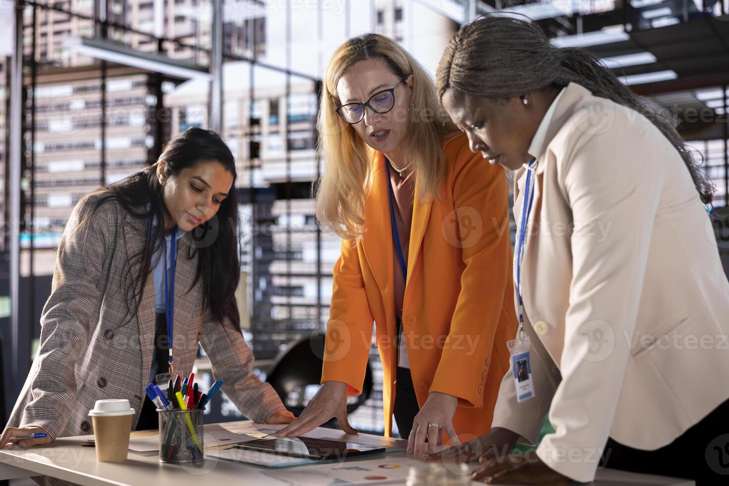 Diverse team of empowered women executives discussing corporate strategy and business growth. Examining analytics to obtain funds for projects, showcasing leadership skills and gender equality. photo