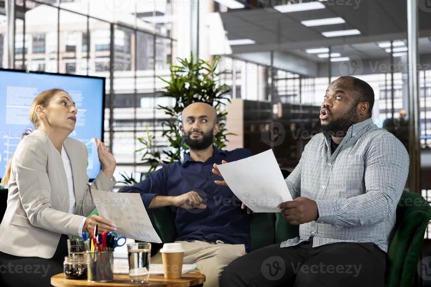Upset diverse team of employees arguing after making mistake while writing revenue figures on documents in office. Mad staff members fighting during dispute over company statistical numbers photo