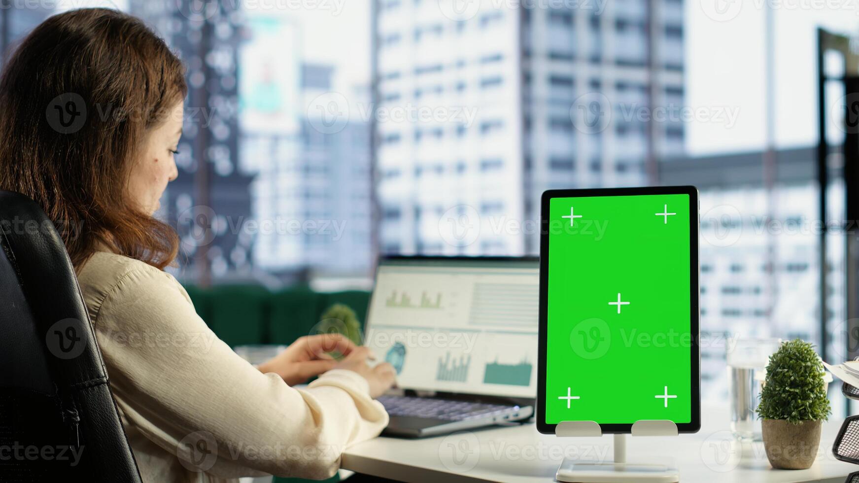 Young business manager working with isolated copy space on her tablet, working on financial planning with data analytics on laptop. Developing a strategy to increase funding for success. Camera B. photo