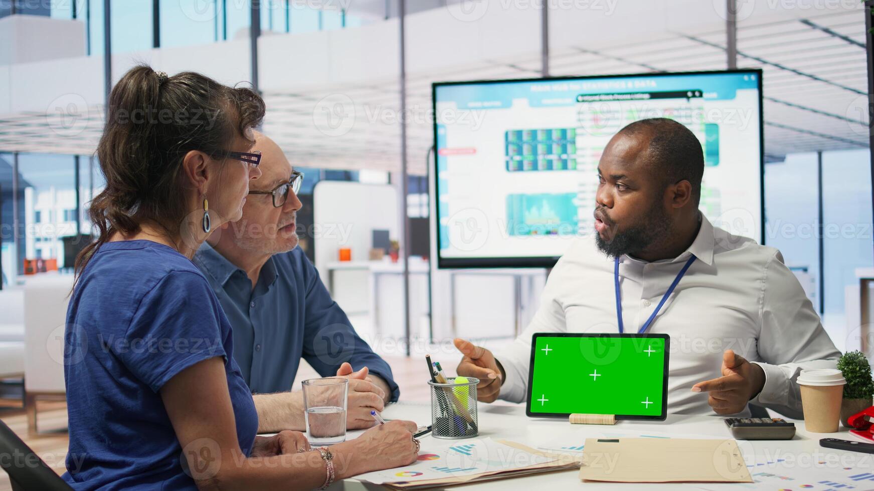 Financial advisor works with a green screen at table with his senior clients, presenting retirement plans and investment options to secure their pension and life savings. Insurance agency. Camera B. photo