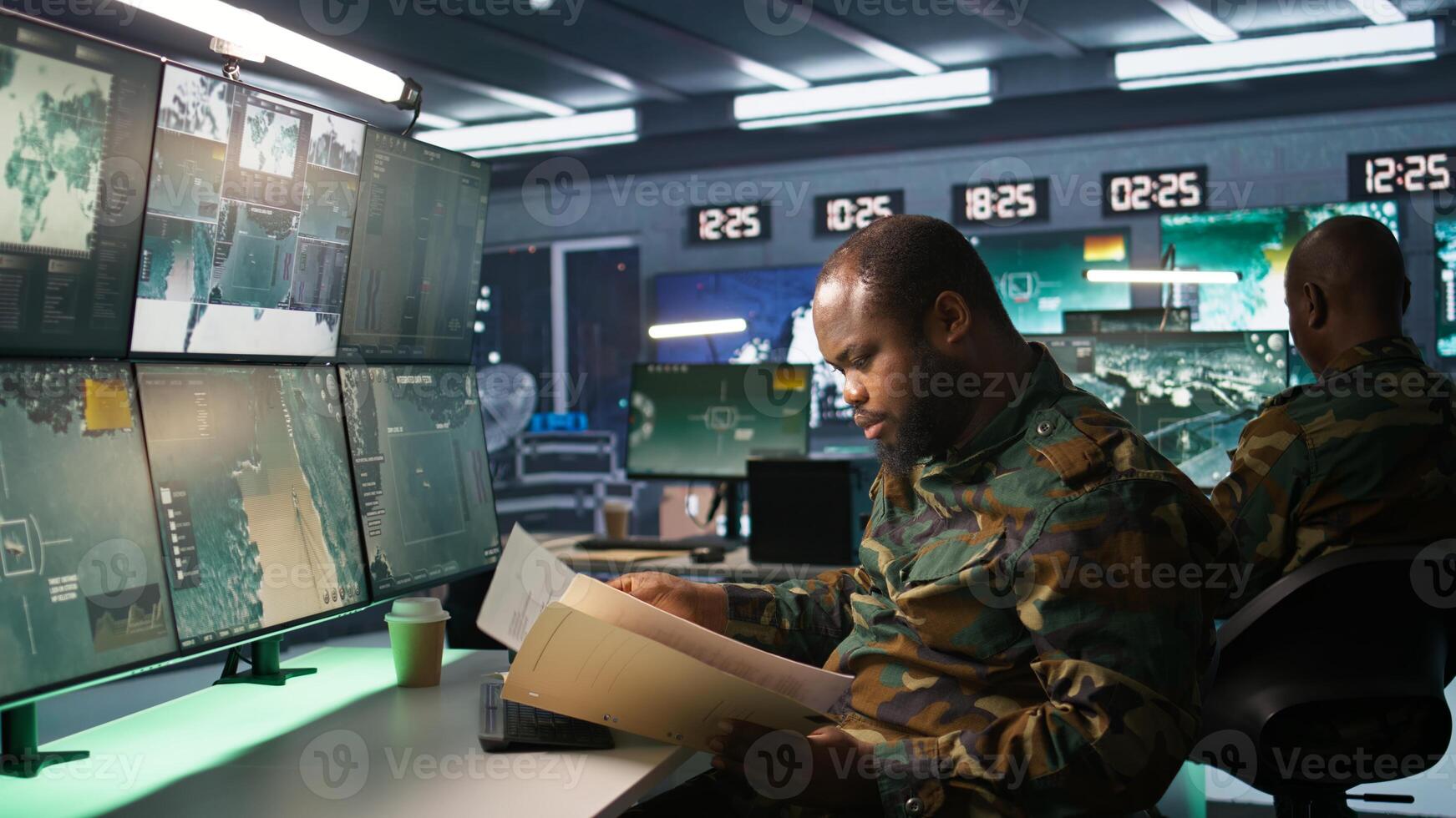 Military soldier in mission control center overseeing national safety operations, reading folder files. African american army specialist checking data in monitoring room command center, camera B photo