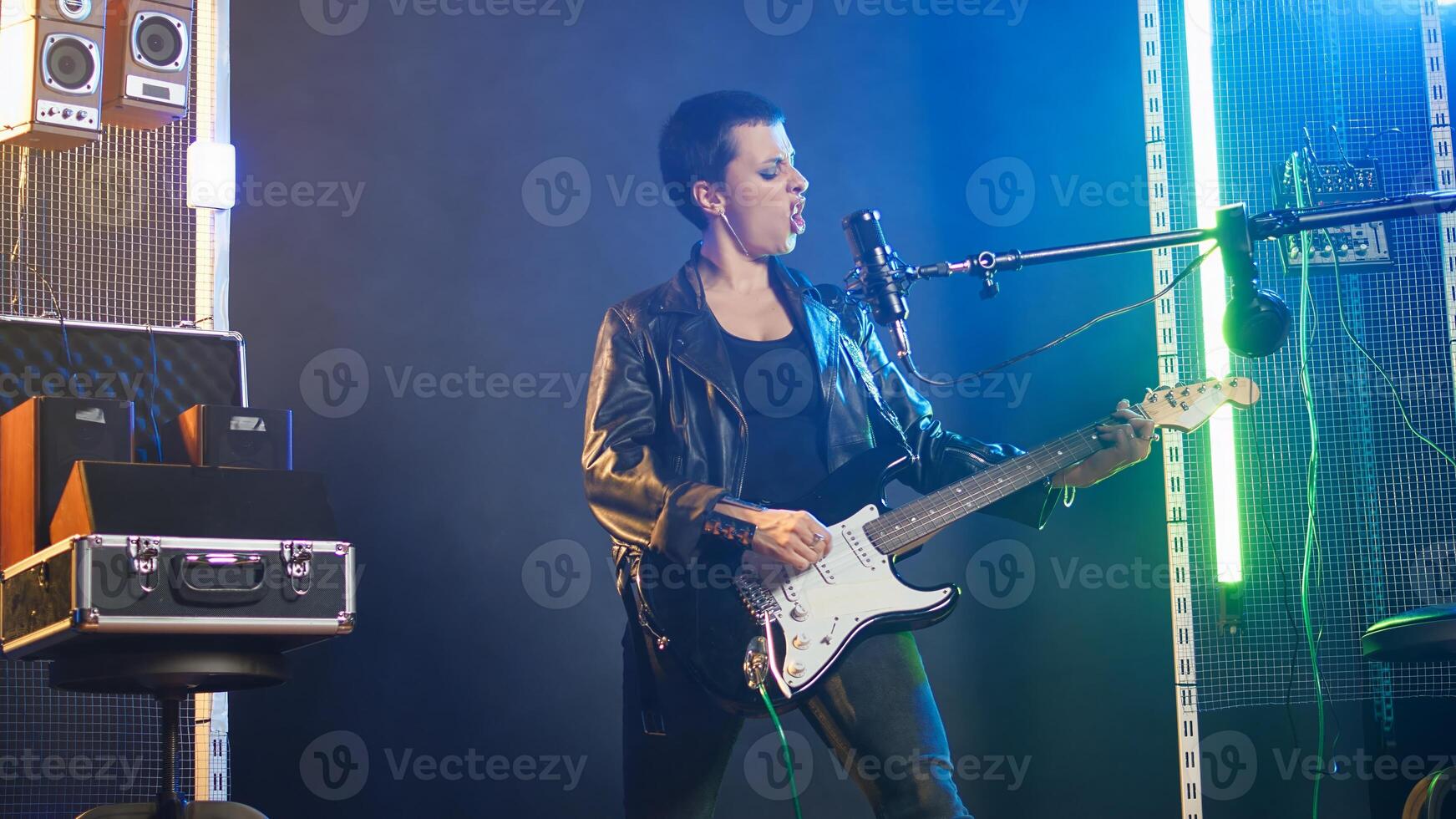 Confident musician performing live in a spotlight illuminated studio, surrounded by audio equipment and lights. Rocker doing a live performance in a rebellious style, bold attitude. Camera A. photo