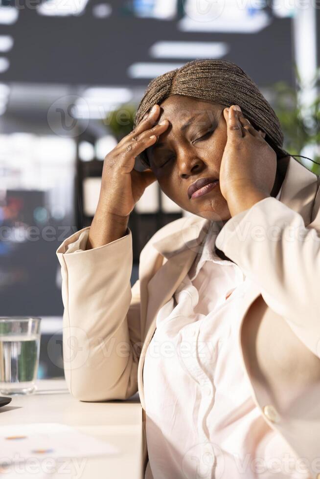 Office clerk having headache from stress while looking through financial business documents over accounting figures. Tired worker in pain, feeling discomfort, working late, suffering sleep deprivation photo