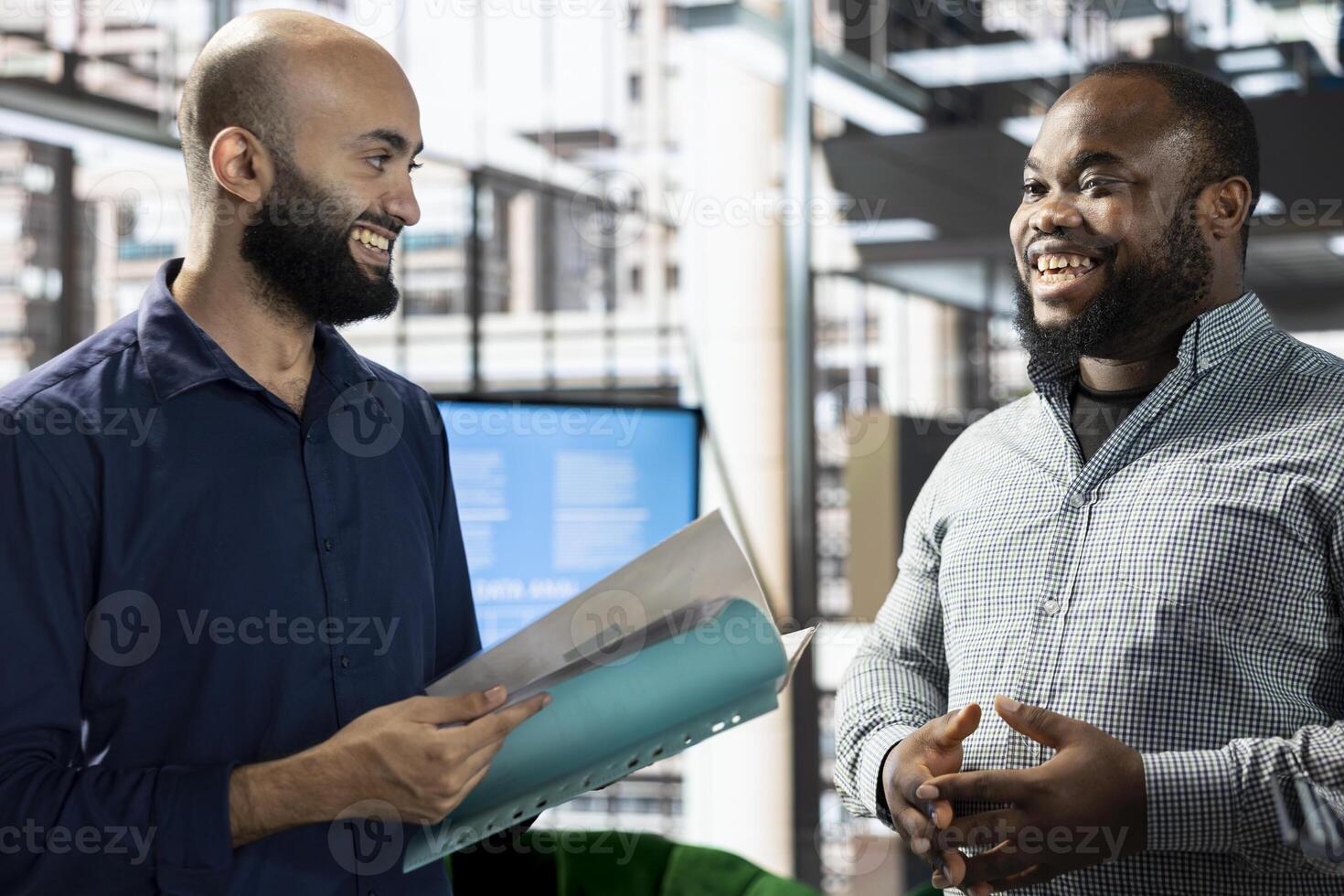 Upbeat startup CEO attends meeting to talk about new business vision with executive board member, presenting him documents. Joyous employee holding files, pitching investment strategy to manager photo