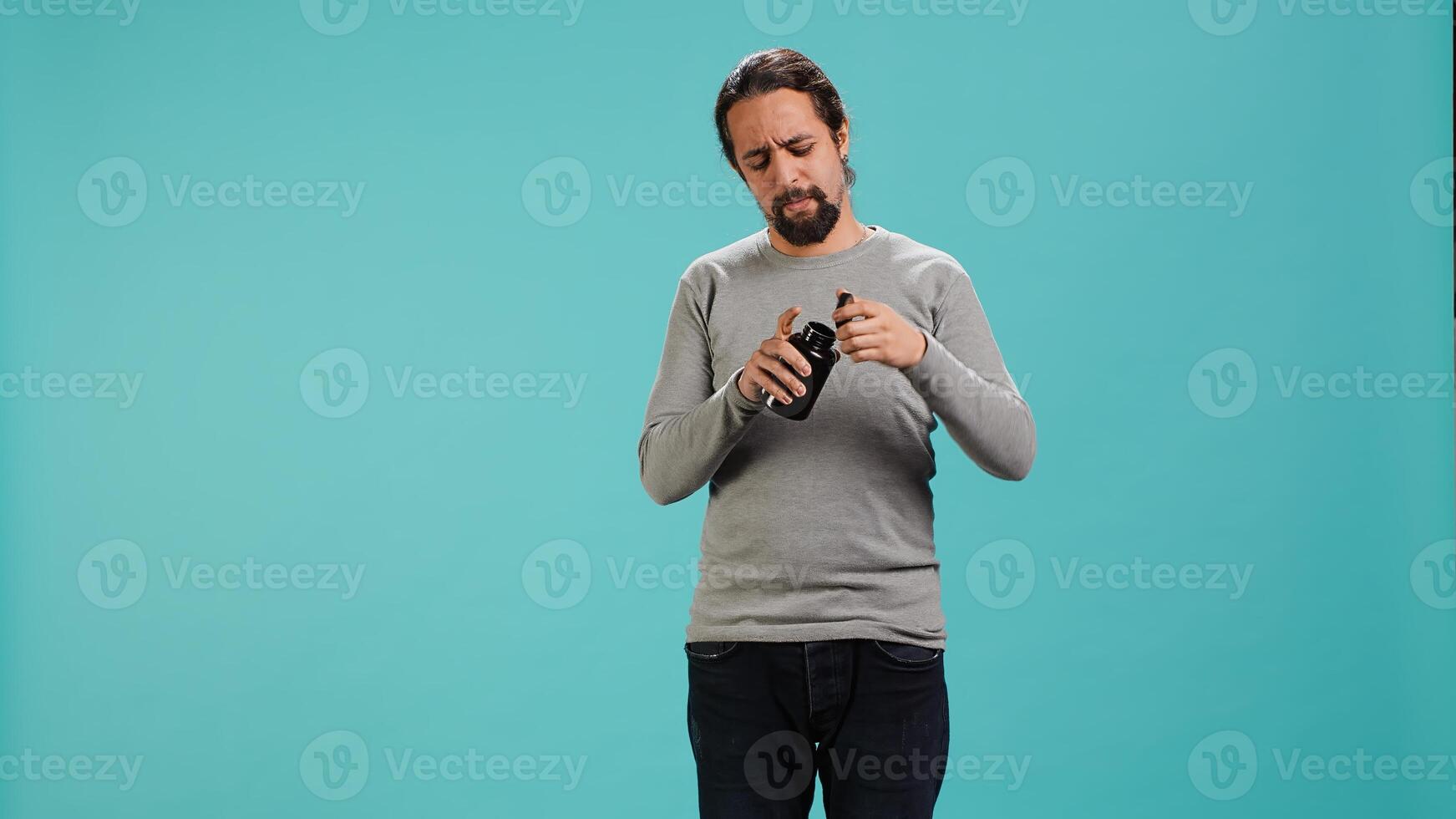 Man hurting from headache taking aspirin, feeling instant relief, isolated over studio background. Sick person feeling ache taking painkillers, amazed by how fast it cured him, camera A photo
