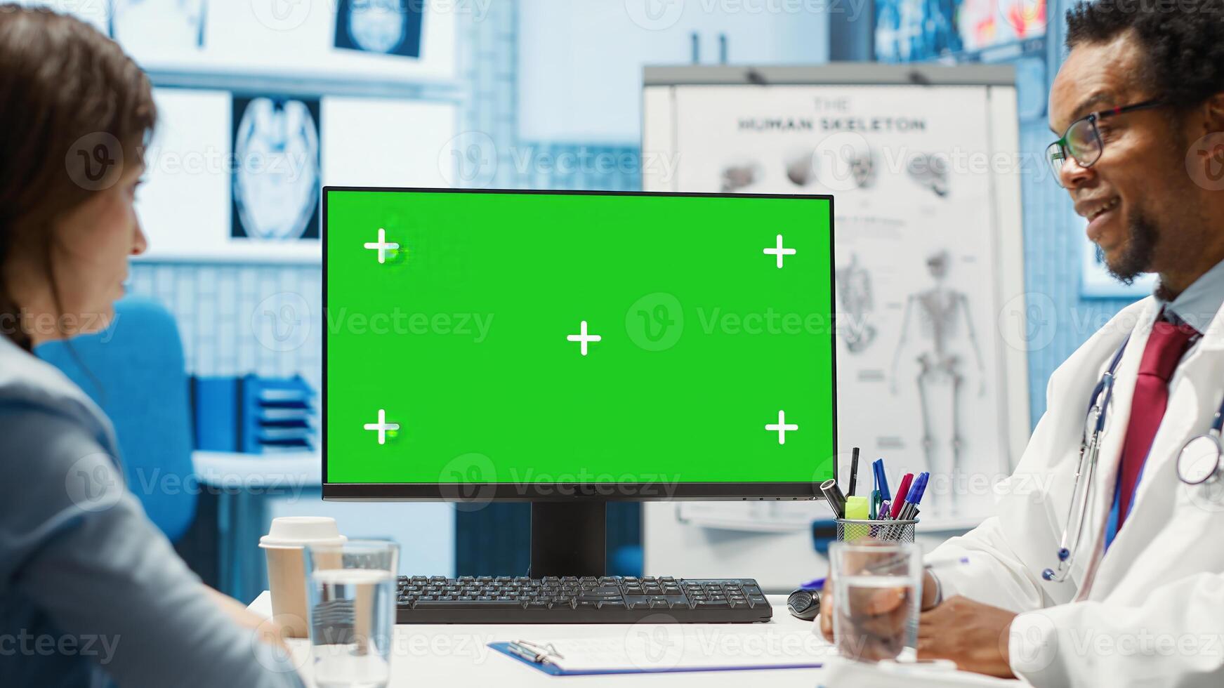 General practitioner consulting a female patient next to isolated chroma key display, sharing insight on lab test results and analysis. Skilled medic supports his client, indoors check up. Camera A. photo