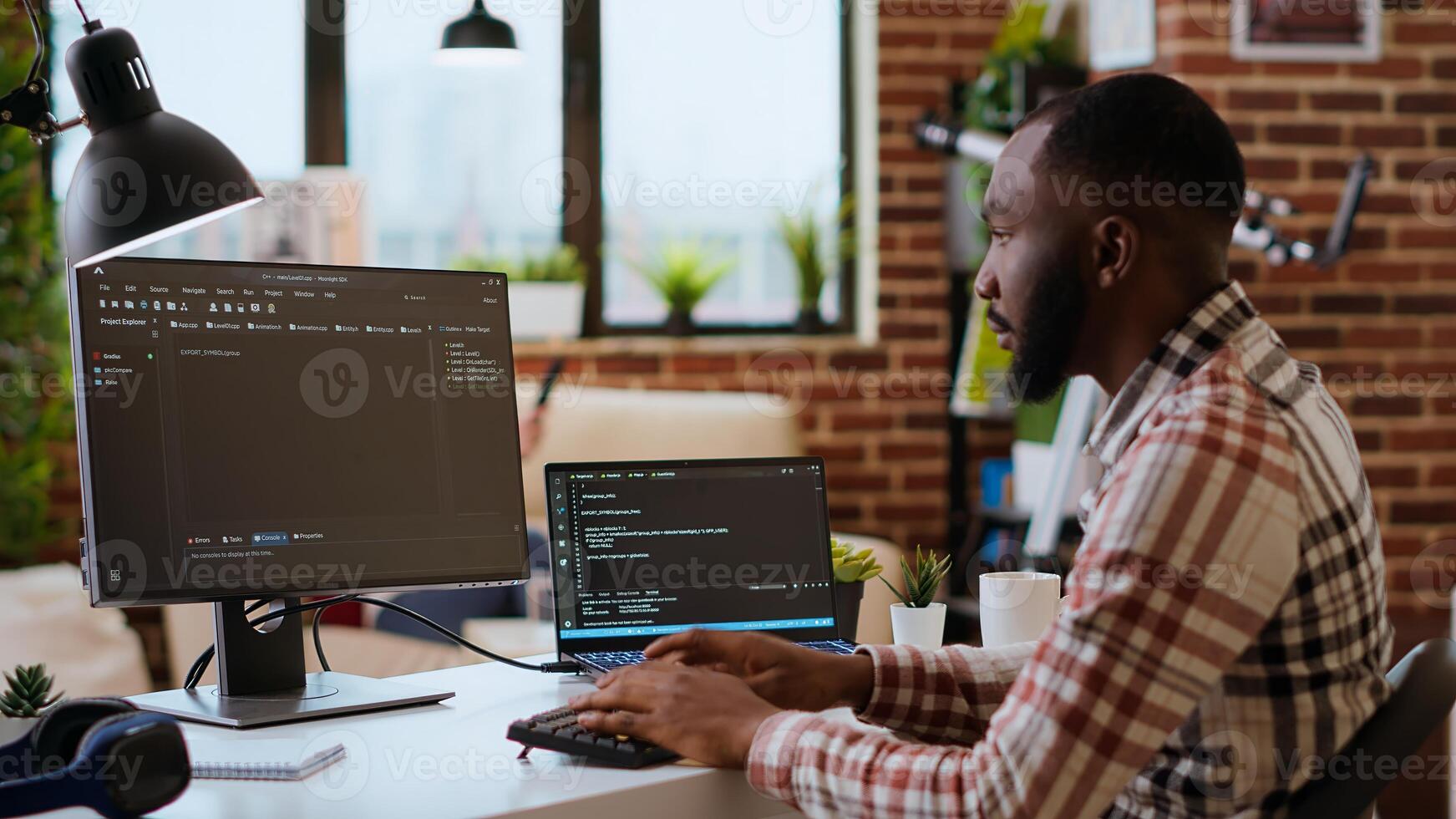 joven hombre visto programación software código en su ordenador portátil en un pulcro hogar oficina. espacio de trabajo con doble monitores ayuda con software ingeniería, web desarrollo y codificación productividad. cámara b. foto