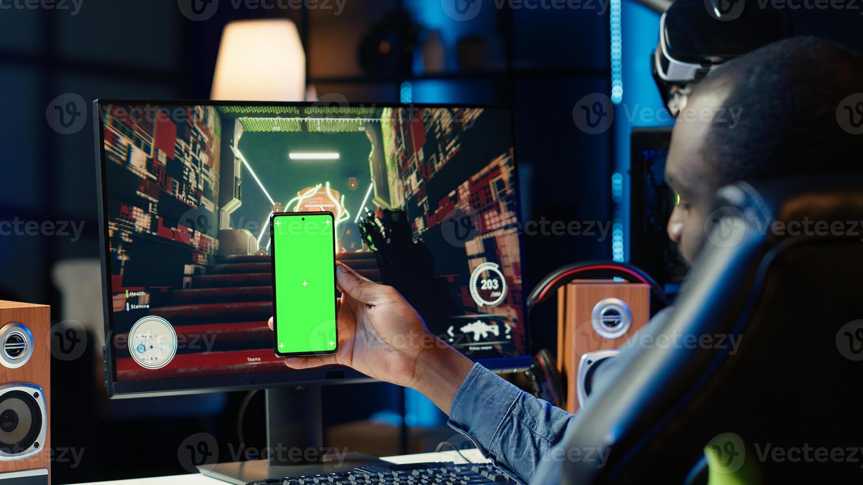 Man texting friends on green screen phone while playing first person shooter videogame at home. Gamer looking at mockup smartphone display, enjoying online discussion with mates photo