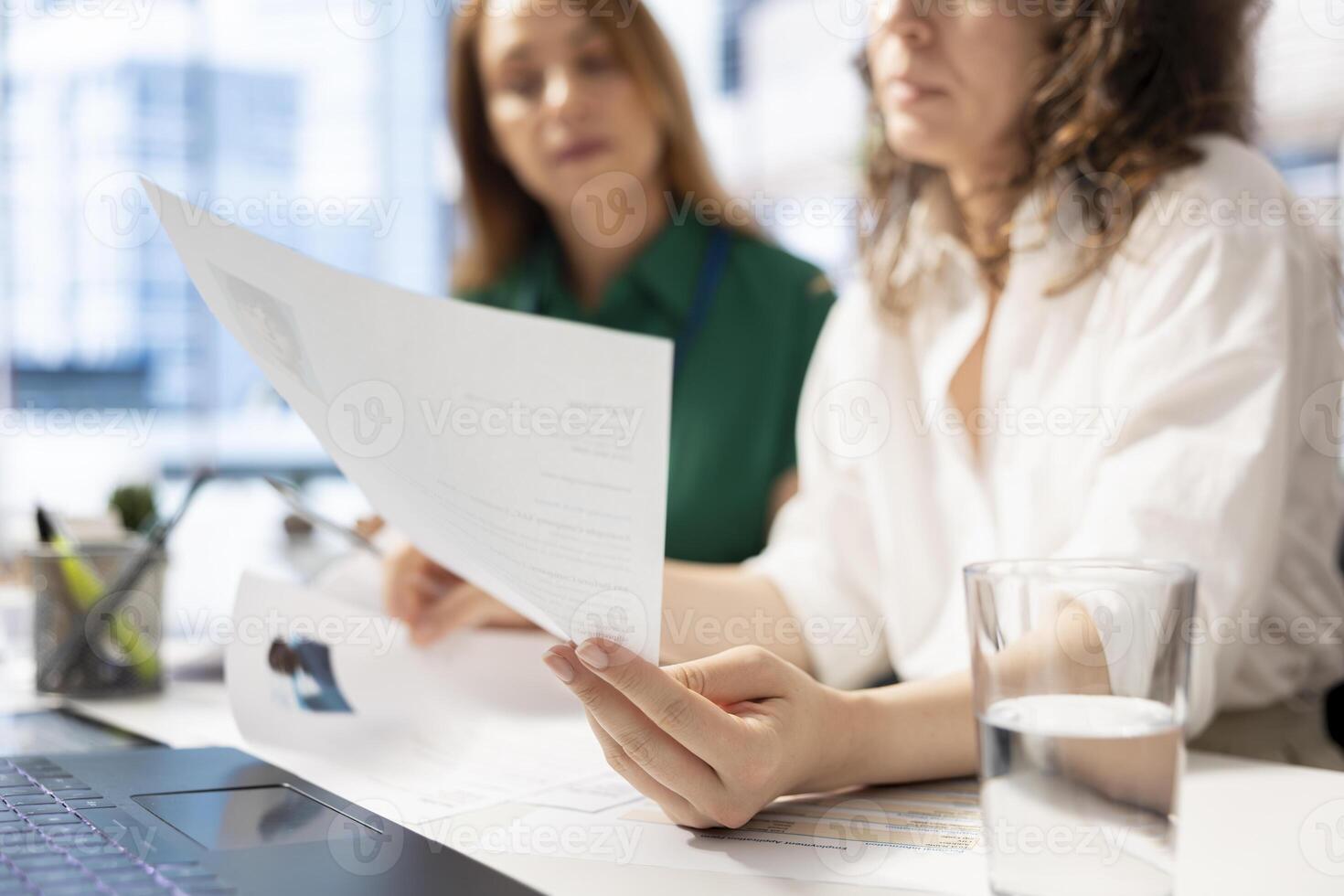 HR colleagues doing screening, looking at CV files to determine if candidates posses skills and experience needed to fulfil the role. Recruiters browsing resumes, evaluating applicants photo