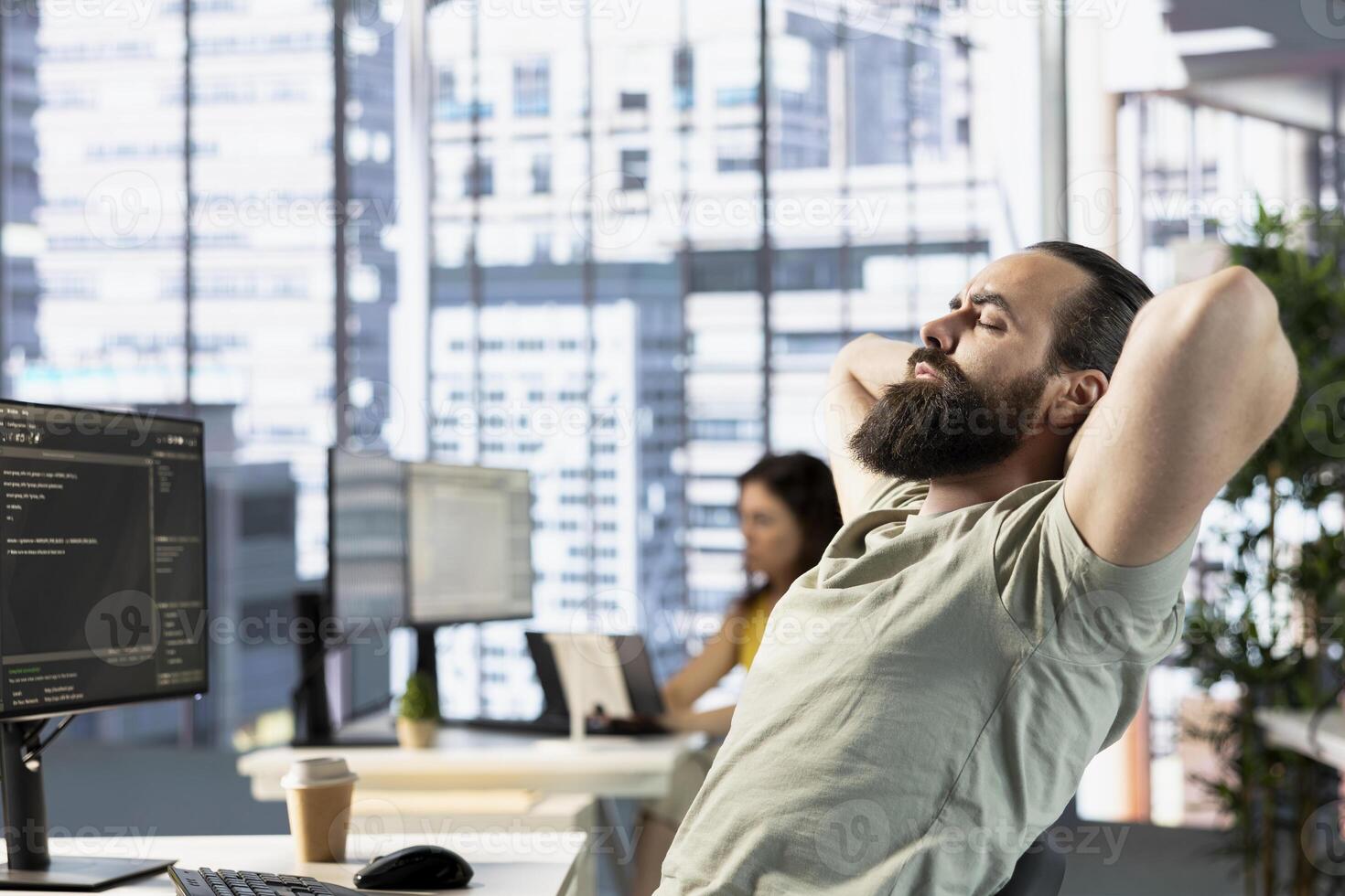 Fatigued admin fixing bad posture while managing cloud computing platforms to train machine learning models. Tired man stretching, trying to relax while monitoring and maintaining company systems photo