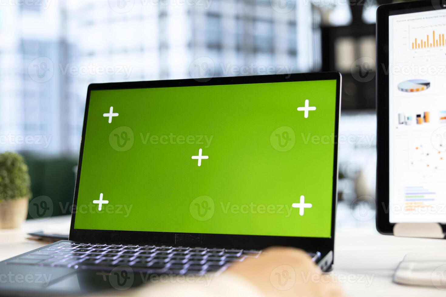 Young business entrepreneur looking at green screen mockup on her gadgets, working in modern urban corporate office. Female leader developing a strategy to increase funding for success. photo