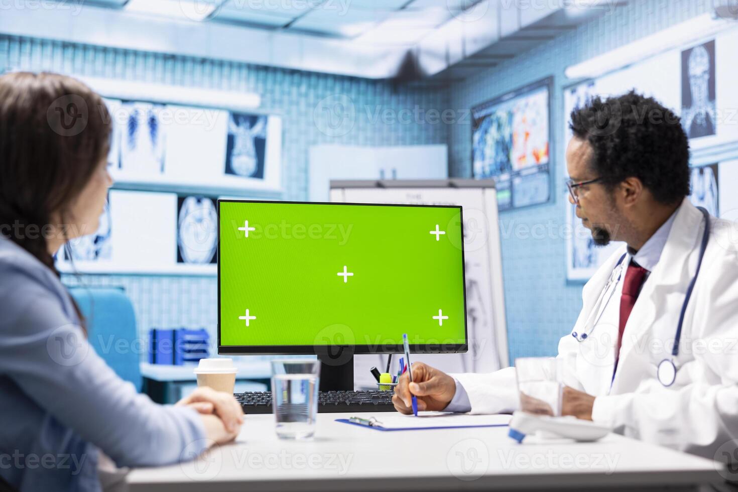 African american medic points at green screen on computer while he consults his patient, exploring treatment plans on health insurance. Physician gives medical advice to ill woman. photo