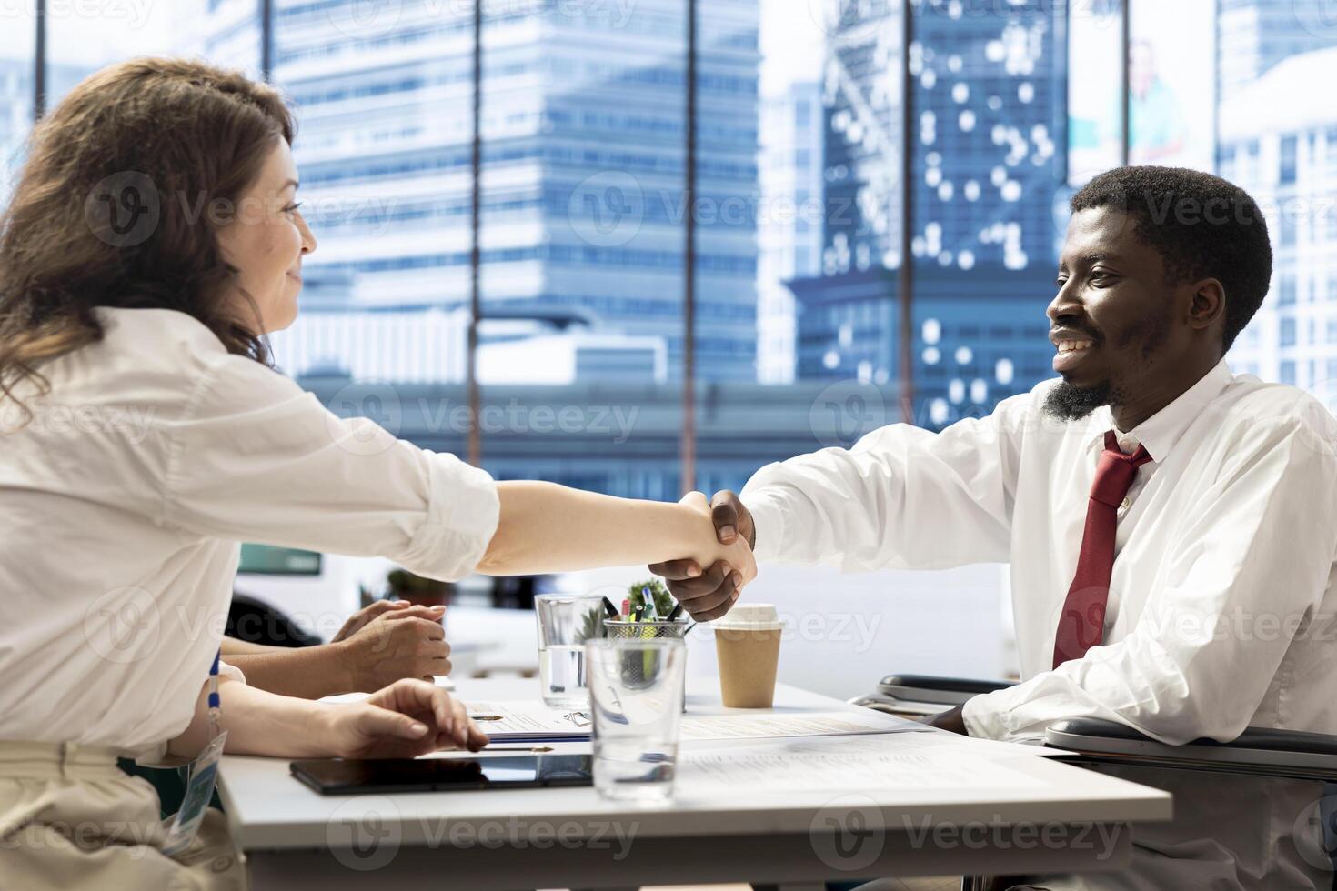HR expert doing handshake with person with disability, vetting applicants to ensure skills match role needs. Headhunter talking with man in wheelchair, shaking hands after assessing work experience photo