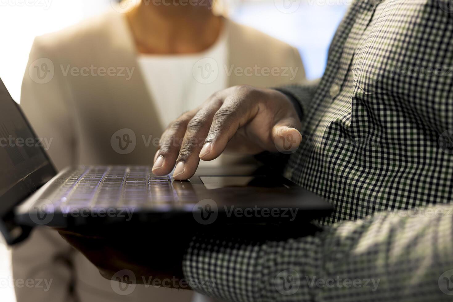 Team of office clerks using laptop to write emails, solving tasks. Close up of workers typing on notebook keyboard, making sure documents are compliant with quality assurance standards photo