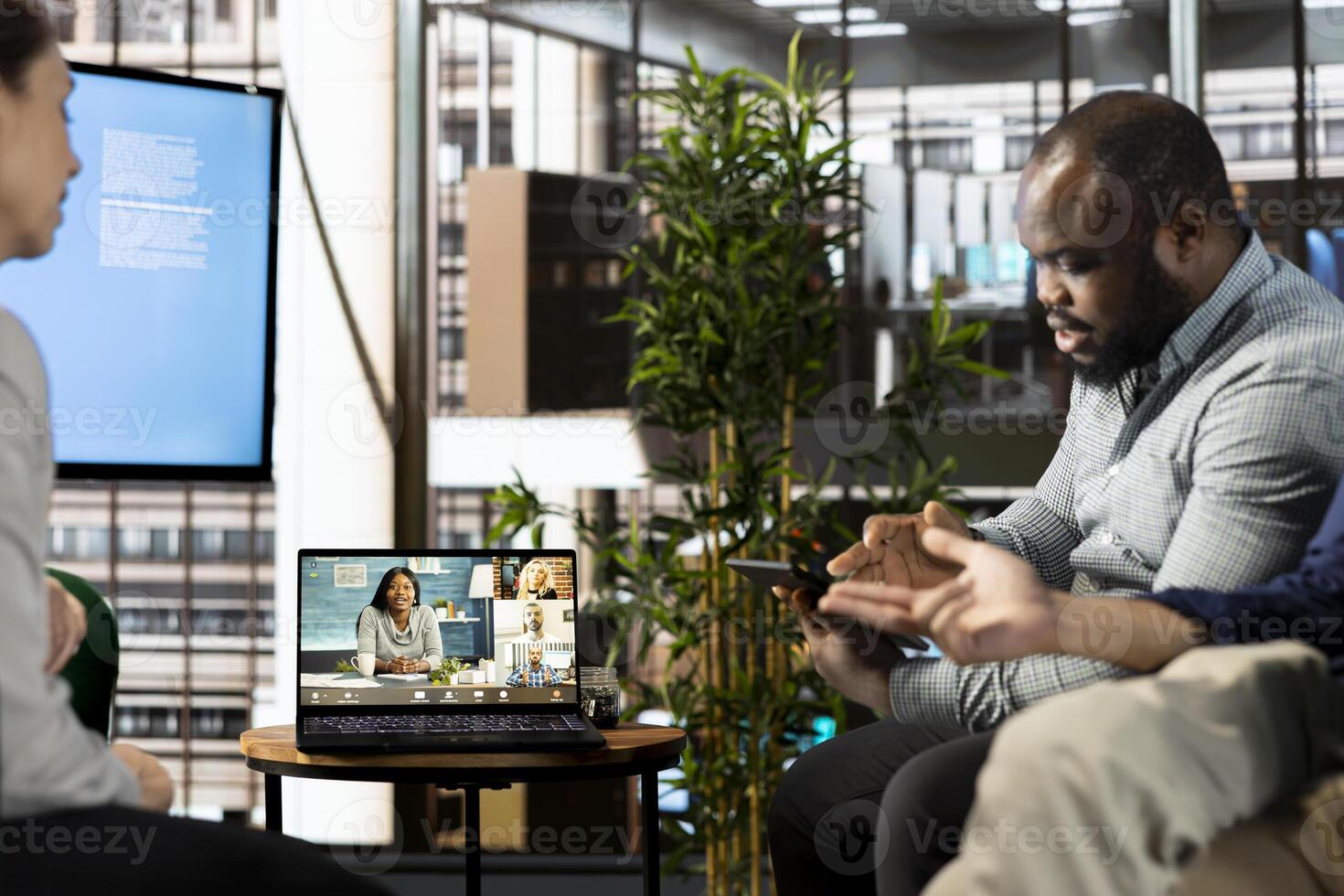 African american man doing videocall with colleagues in company office. Worker talking over remote videoconference meeting with business partners inquiring about commissioned project progress photo