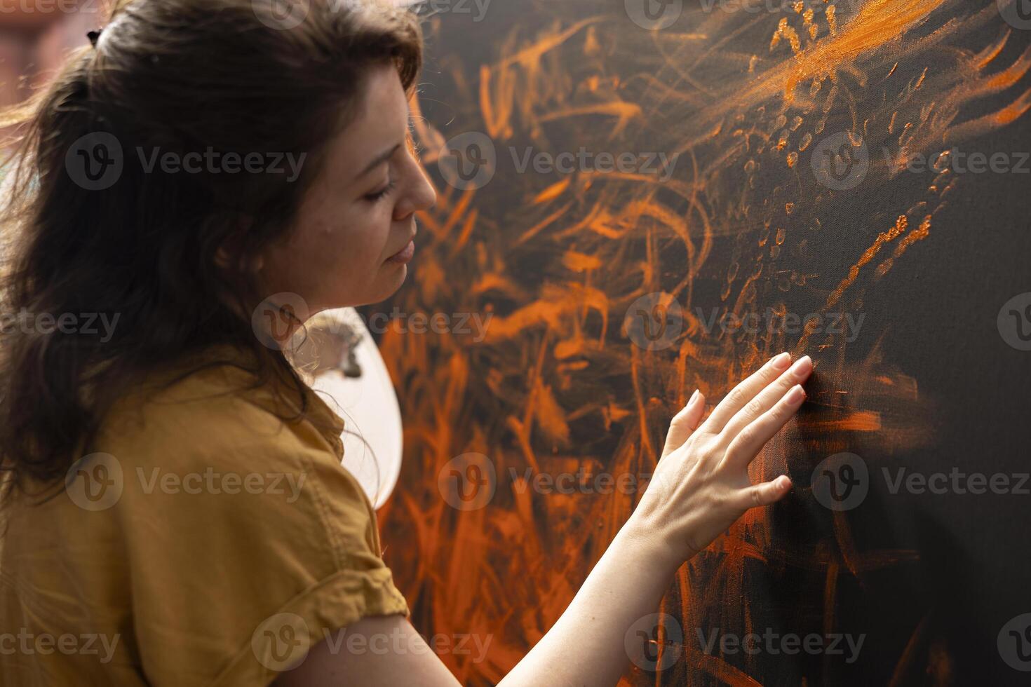 In an art studio, painter uses watercolor paint to create a finger painted masterpiece. Creative talented artist showing her inspiration to create a rustic colorful artwork with handprints. photo