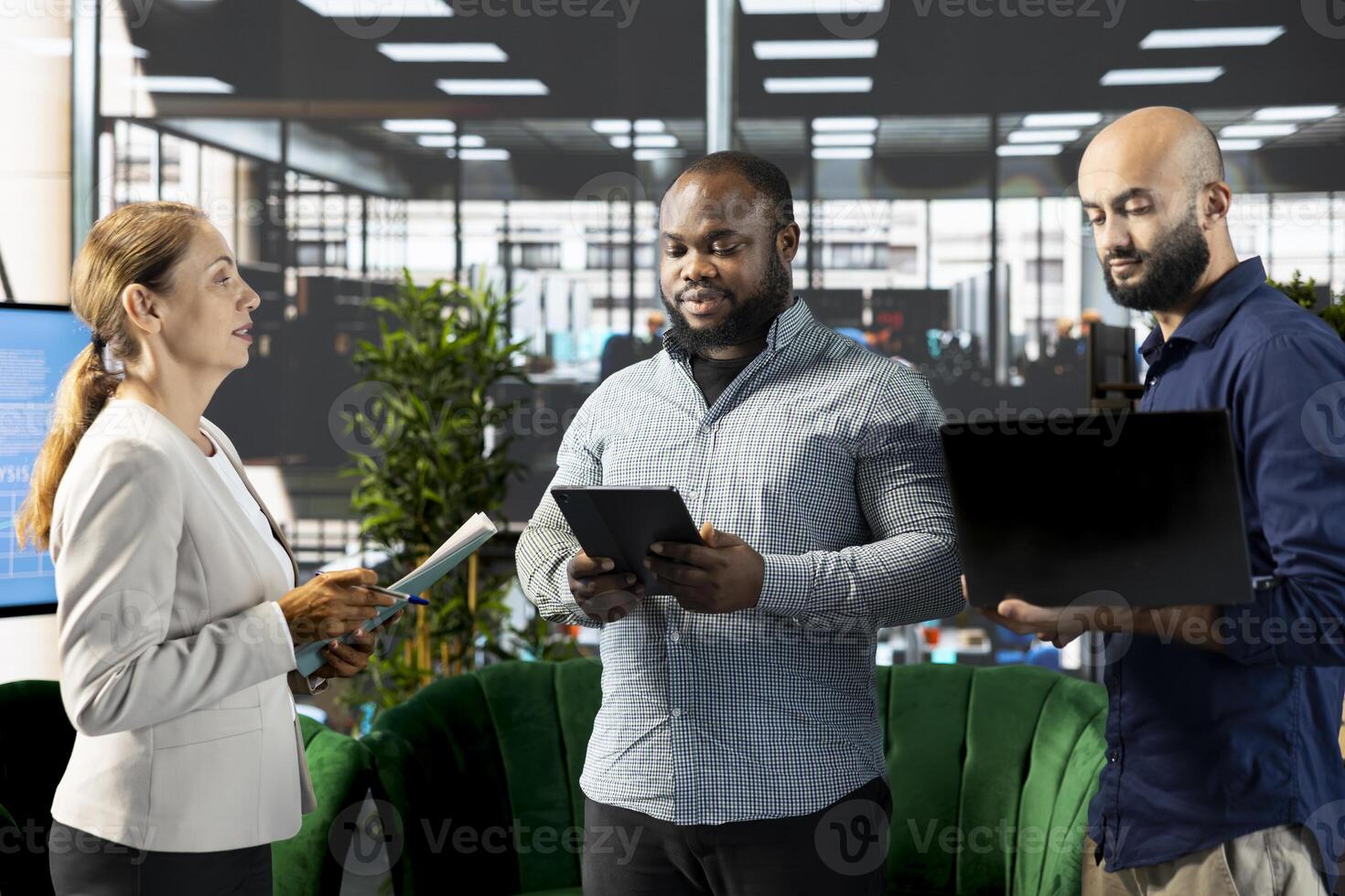 Manager with employees developing business strategies to improve operational profitability using laptop and tablet. Company director setting revenue performance targets using notebook device photo