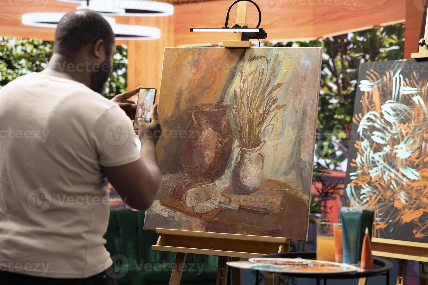 Skilled painter recording a of his finished creation for self promotion, using his online presence for digital marketing and fame. Feeling proud of his new artwork content creation. photo