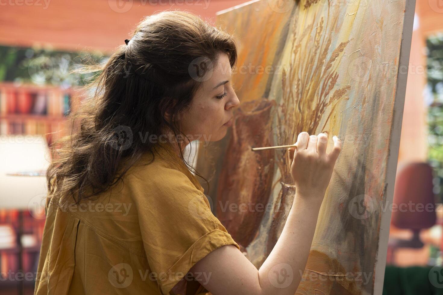 Inspired artist works on a canvas to create a masterpiece in atelier, using bristles to apply dye with precision. Showing her skill during creative process to create unique painting for the gallery. photo