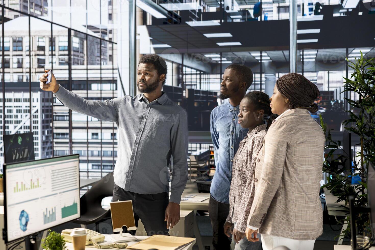 Black corporate employees smiling at photos on smartphone in the office, taking a break from business tasks or operations and enjoying pictures. Friendly happy employees in an enterprise.