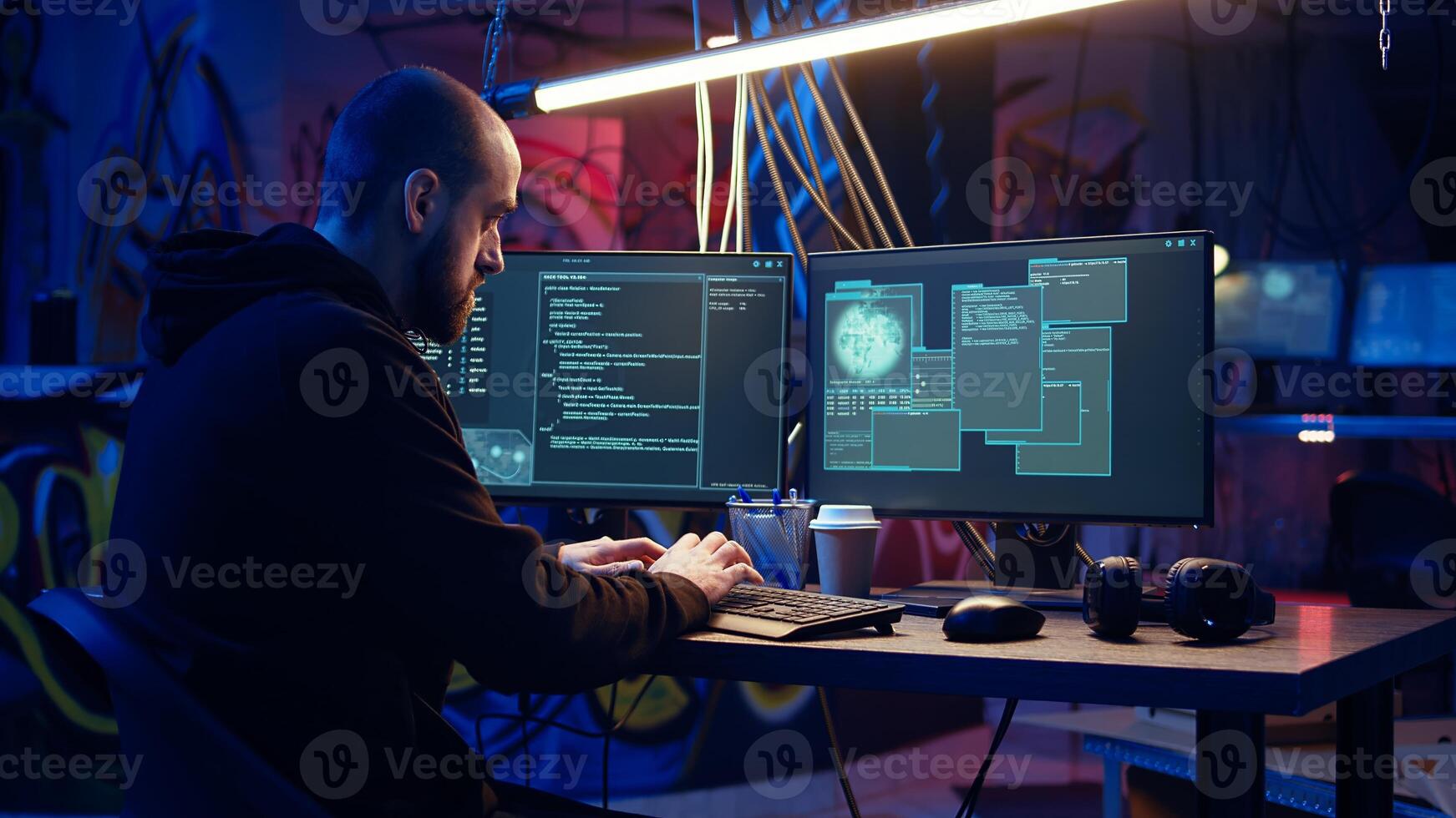 Hacker in underground warehouse writing lines of code on computer screen to make malware that get past security systems. Man in hidden HQ building scripts that can hack devices, dolly in shot photo