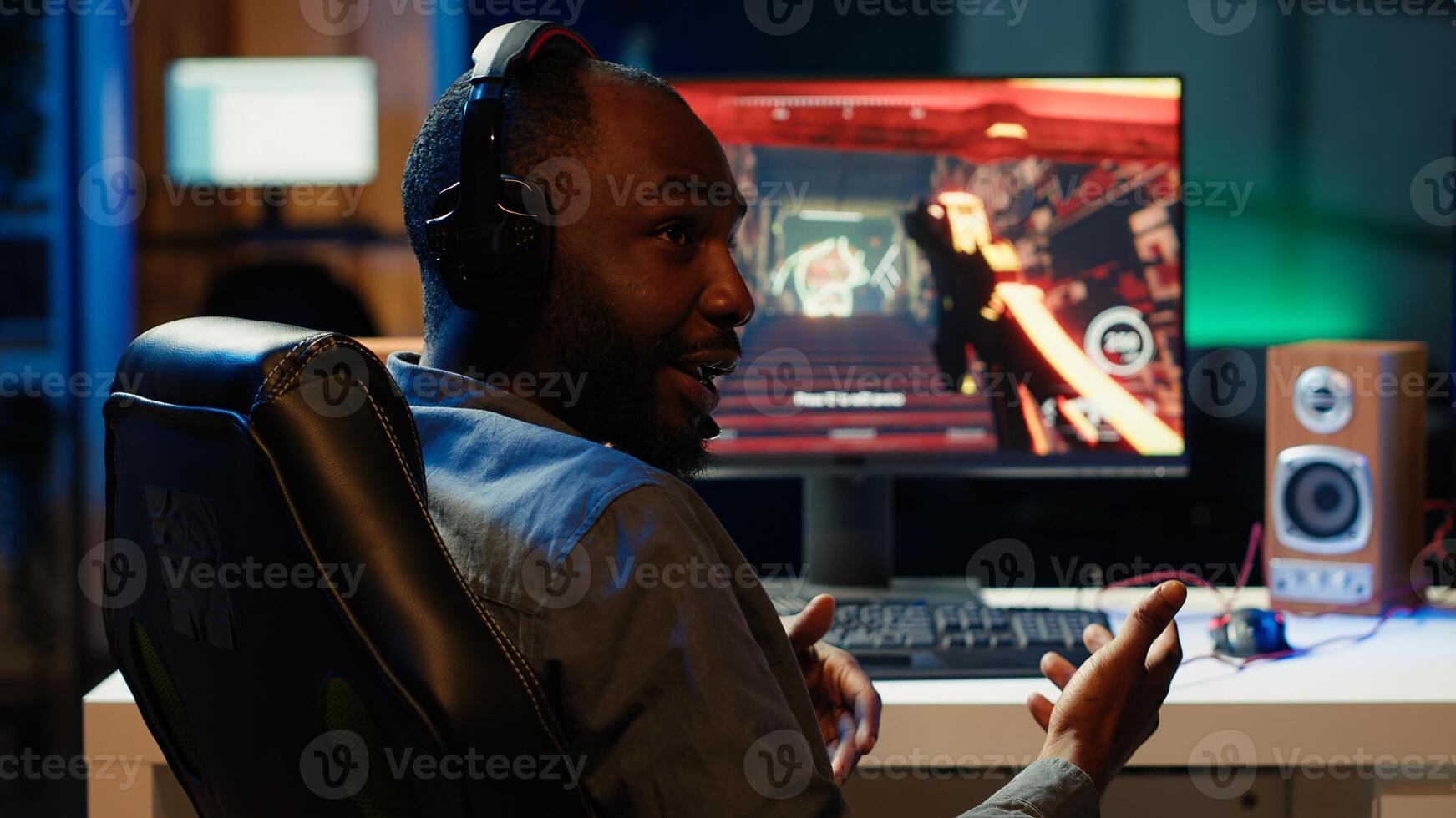 Professional streamer showing fans how to win intense online multiplayer videogame, streaming live at home. Man playing on gaming PC, using headphones to talk with audience, camera A photo