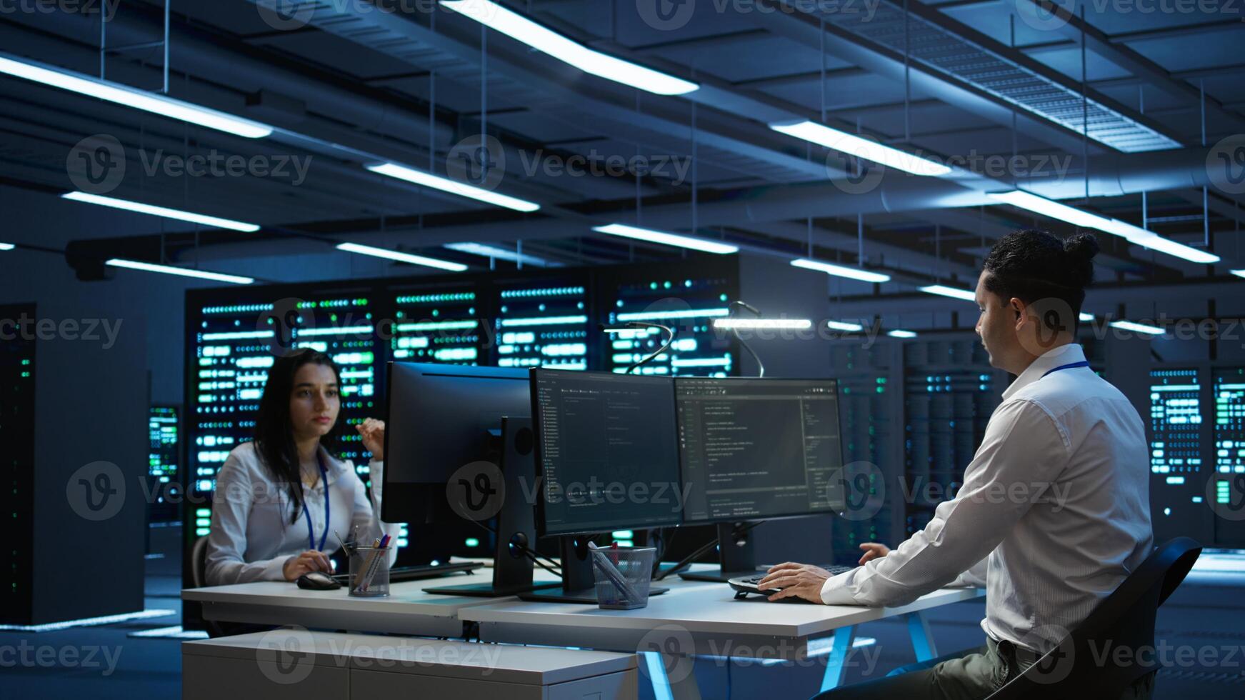 Engineer in data center installing software on computer, troubleshooting issues, handheld camera shot. IT professional in server hub establishing performance benchmarks, camera B photo