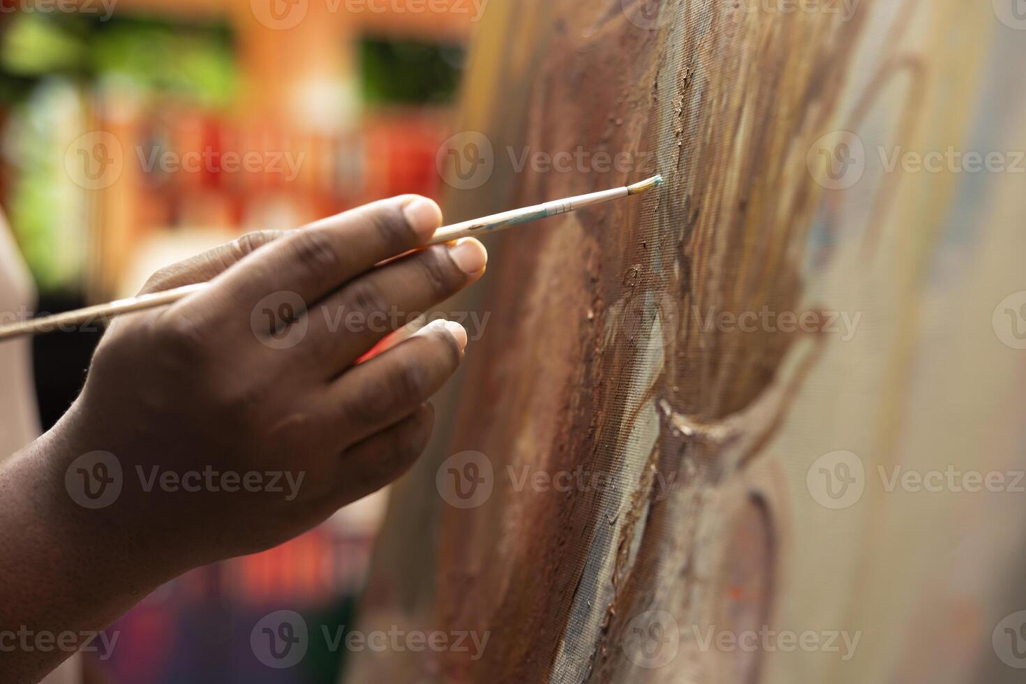 African american artist applying acrylic dye with his paintbrush on canvas, showing his skill in creating a masterpiece for the art gallery. Working with professional supplies. Close up. photo