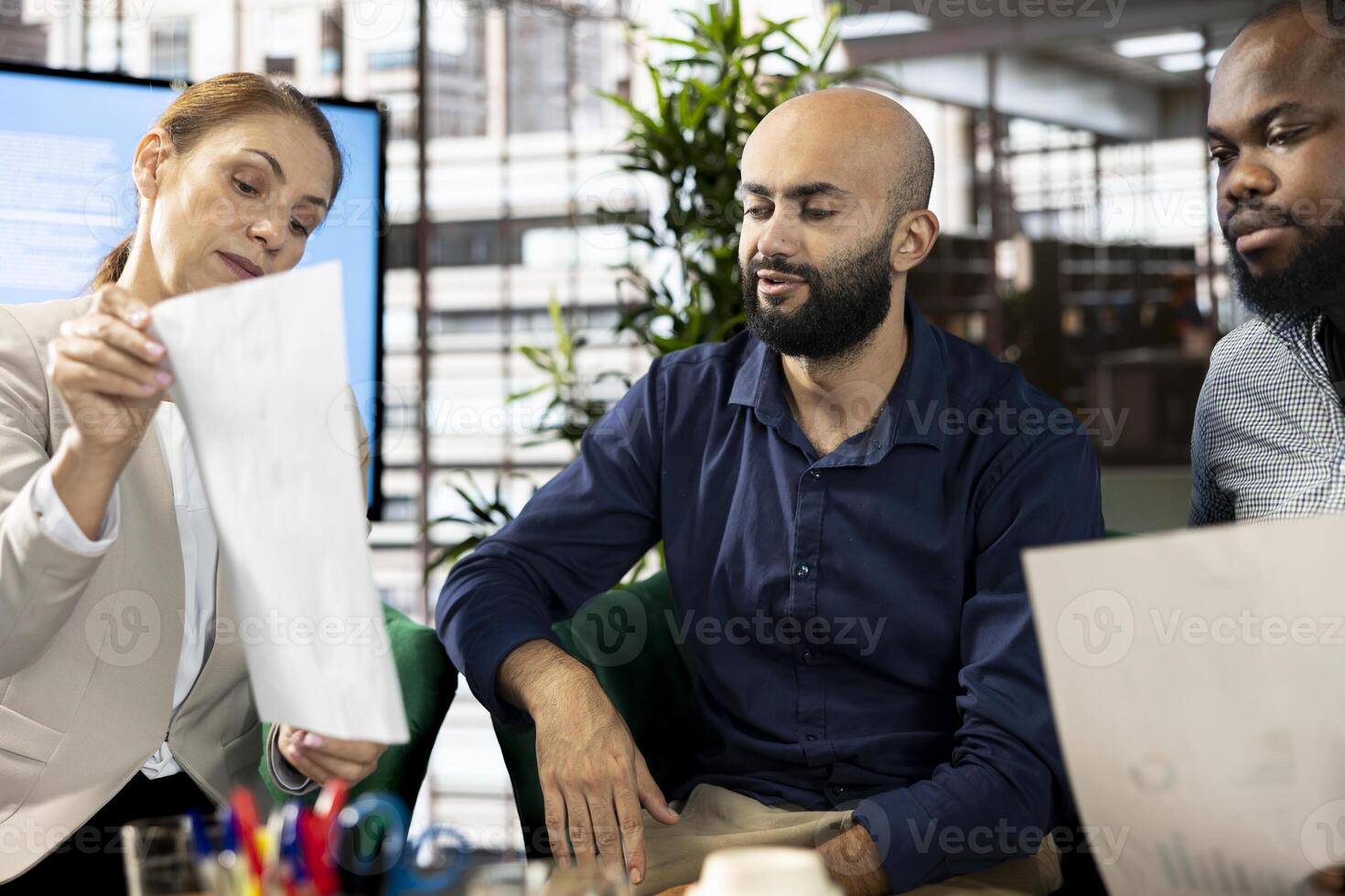 Office clerks showing Middle Eastern manager company documents, checking progress on customer commissioned project. Workers presenting key data statistics files to Arab team leader after audit photo