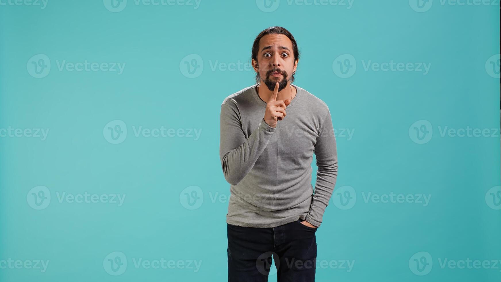 Portrait of man doing shushing hand gesturing, requesting silence. Person placing finger on lips, doing quiet sign gesture, asking for secrecy, isolated over studio background, camera A photo