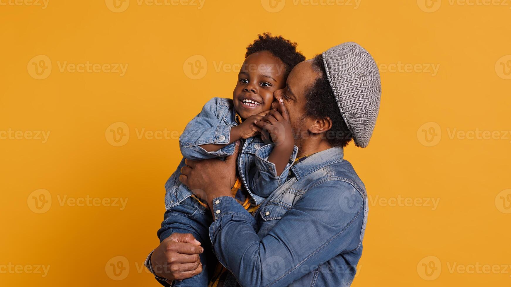 African american father and cute toddler having fun together in studio, dad carrying and embracing him. Young dad does good parenting with his infant, showing love and affection. Camera A. photo