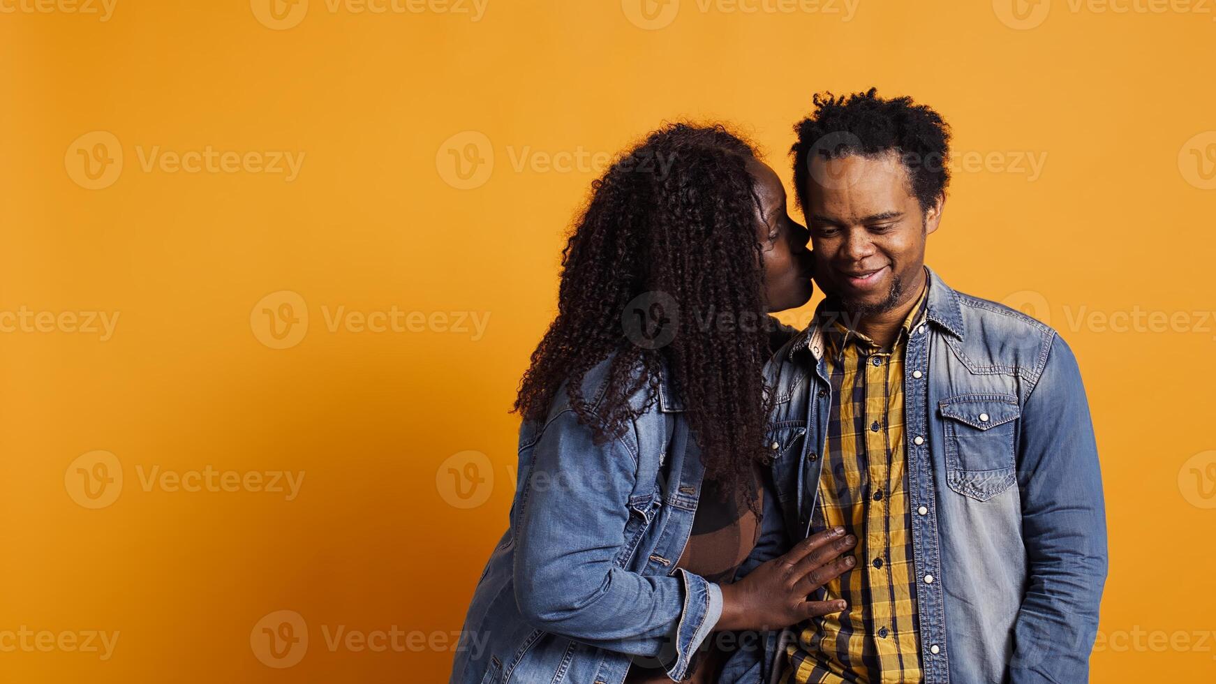 Funny wife making her husband laugh about sweet nothings, whispering things into his ear and amusing each other. Cute romantic married couple having secrets in studio. Camera B. photo
