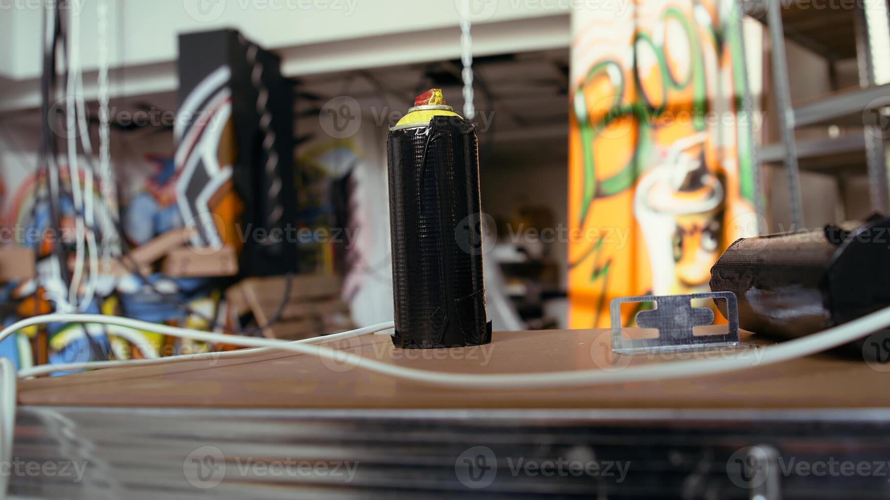 Close up of spray cans in empty basement with graffiti drawings on walls. Focus on paint cans with underground warehouse used as crime haven by hooligans in blurry background photo