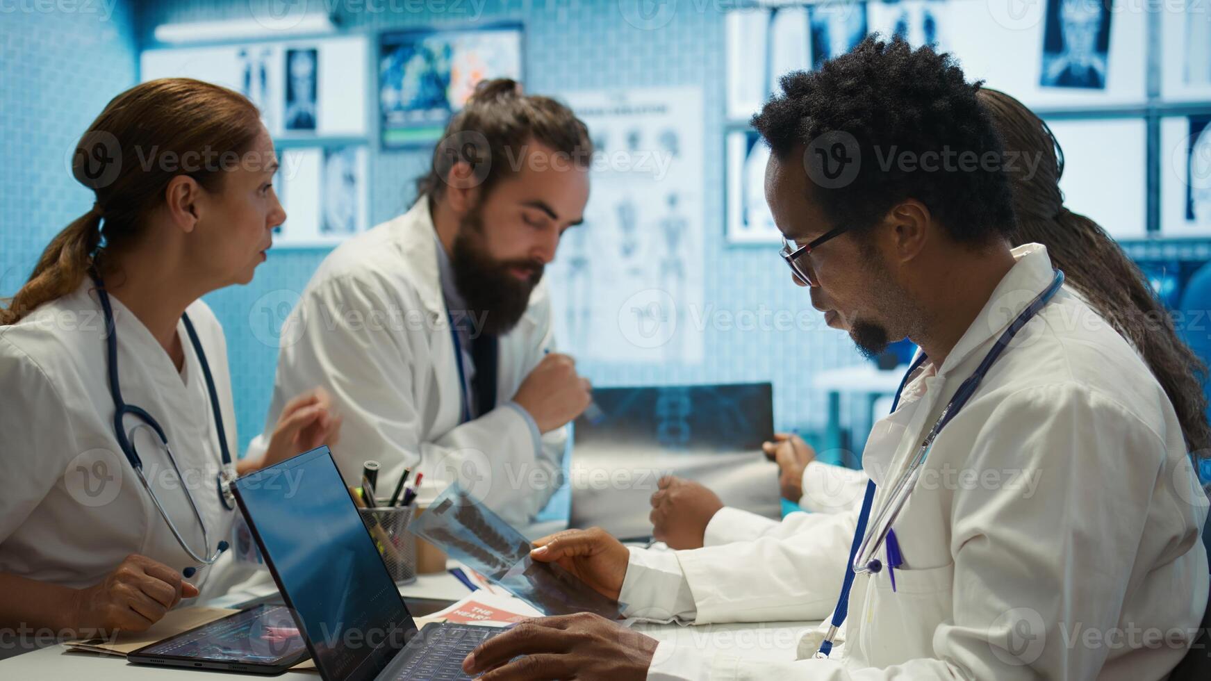 Healthcare experts team reviews x ray results to find best treatment plan, medical office meeting. Collaborative work with expertise in radiology and disease prevention, analytics control. Camera B. photo
