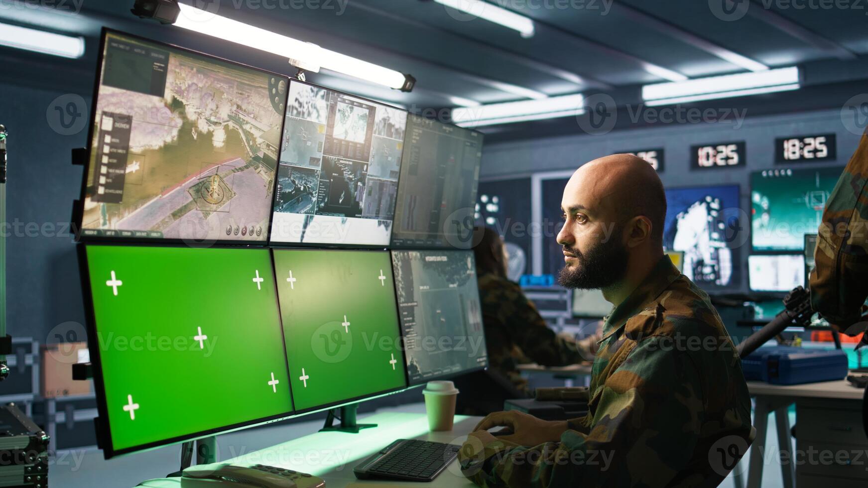 Army specialist working in war room operating surveillance tech, evaluating target data on green screen gear. Man doing job in base of operations, engaging enemy forces using mockup monitors, camera B photo