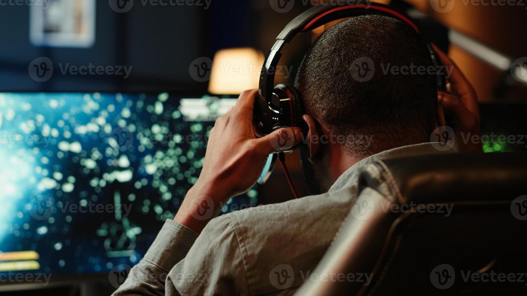 Man playing SF space videogame on PC screen, shooting asteroids, putting headphones on. Close up of gamer enjoying spaceship flying game on computer desktop display, navigating through meteorites photo