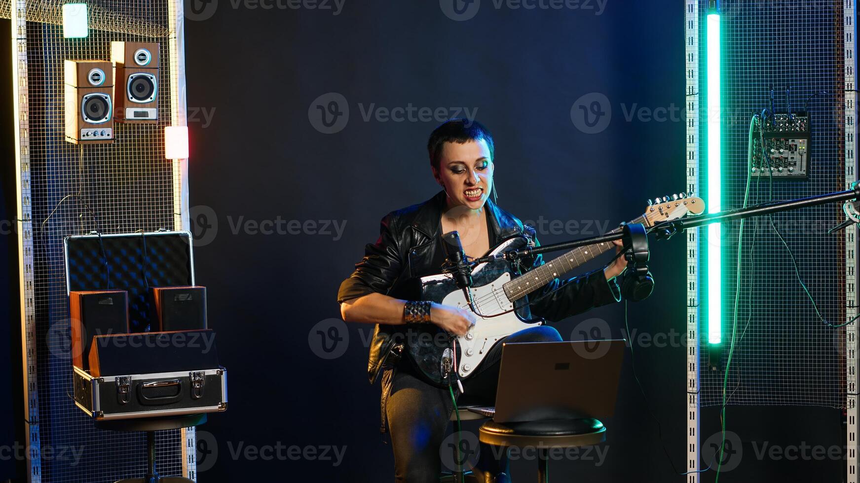 Pleased punk rock artist rehearsing for her live performance, focusing on vocal training and warm up. Edgy iconic woman enjoying singing practice with alternative music. Camera B. photo