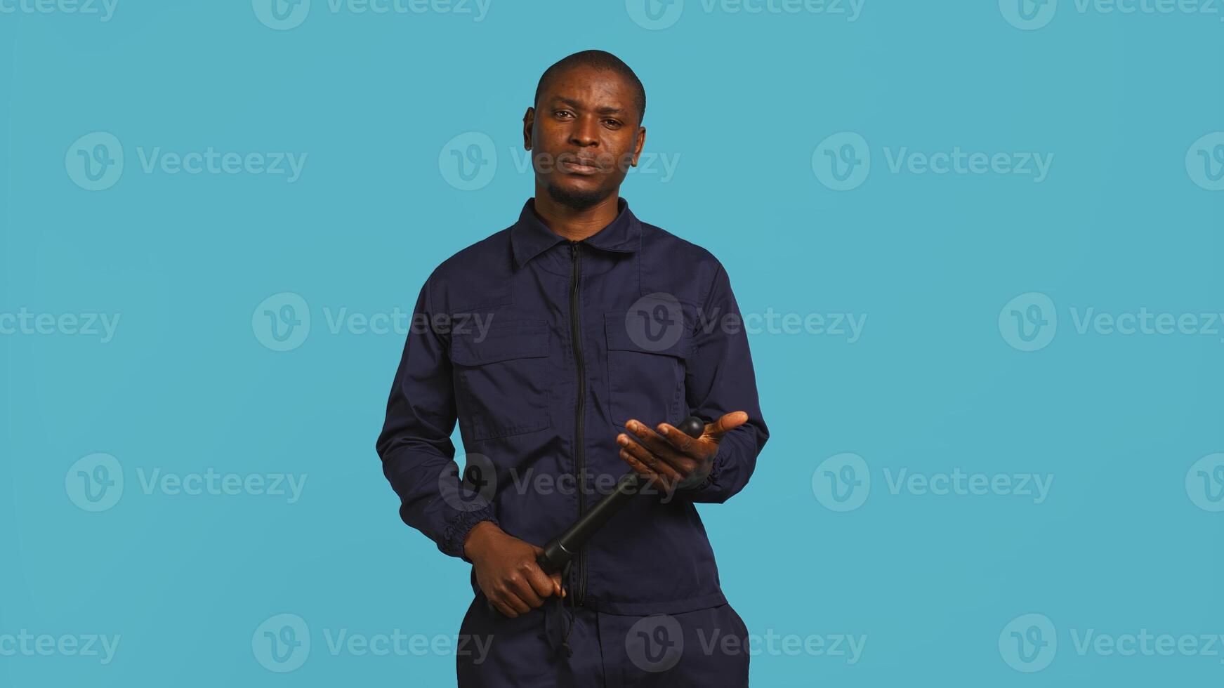 Security guard smacking hand with baton, intimidating suspects. Portrait of bodyguard showing truncheon, threatening to subdue criminals, shaking head, studio background, camera B photo