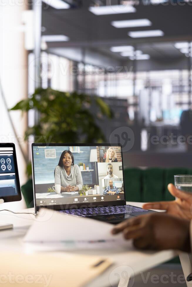 Close up of CEO in startup office holding videoconference meeting with remote workers, discussing project plan. Supervisor at computer desk in internet videocall with employees working from home photo