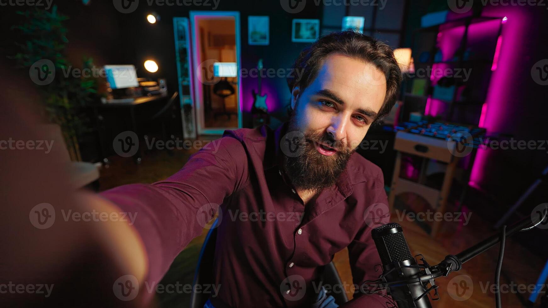 Joyous influencer using professional recording equipment to film vlog channel intro, talking with subscribers. POV shot of upbeat vlogger recording himself greeting fans, covering different subjects photo
